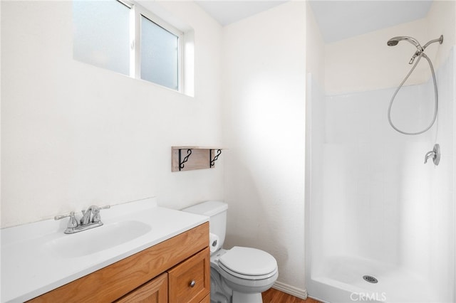 bathroom featuring toilet, a shower stall, and vanity