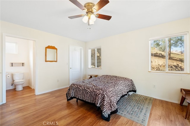 bedroom featuring a ceiling fan, light wood-type flooring, ensuite bath, and baseboards