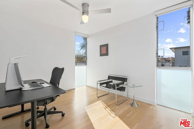 home office featuring hardwood / wood-style flooring, expansive windows, and ceiling fan