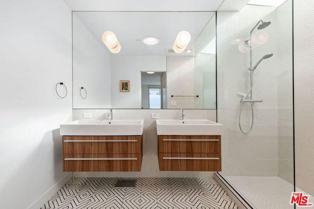 bathroom featuring tile patterned flooring, a tile shower, and vanity