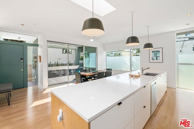 kitchen with pendant lighting, sink, white cabinetry, and a kitchen island with sink