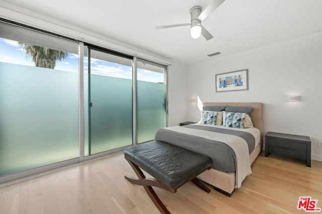 bedroom featuring ceiling fan, expansive windows, access to exterior, and light hardwood / wood-style flooring