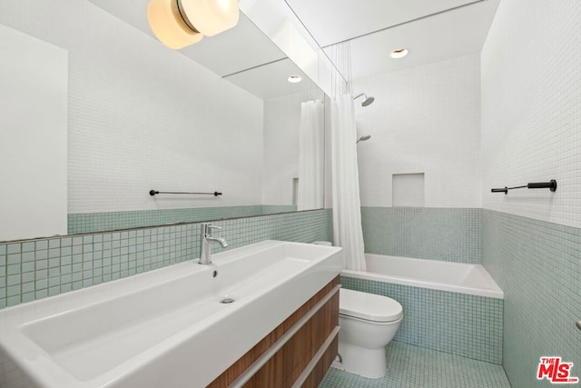 full bathroom with toilet, tile walls, shower / bath combination with curtain, and vanity