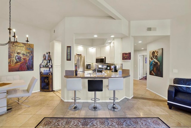 kitchen with kitchen peninsula, a kitchen bar, white cabinetry, appliances with stainless steel finishes, and light tile patterned floors