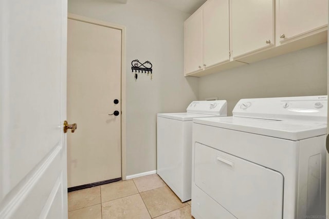 laundry room with light tile patterned flooring, cabinets, and washing machine and clothes dryer