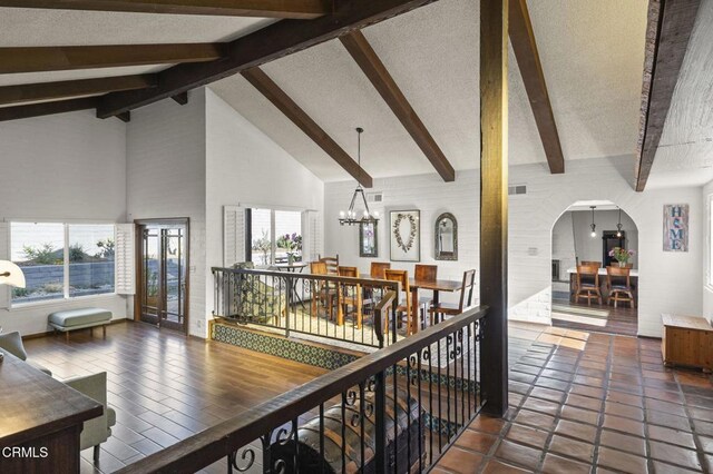 corridor featuring high vaulted ceiling, beam ceiling, and a notable chandelier