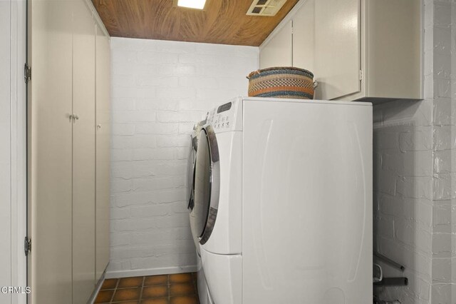 laundry room with washing machine and dryer, cabinets, brick wall, and wood ceiling