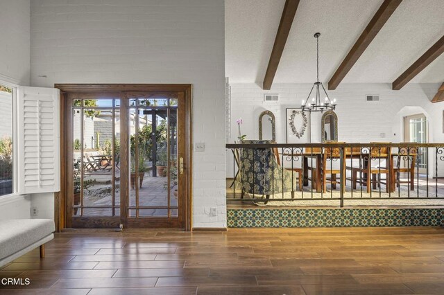 foyer entrance featuring a towering ceiling, a chandelier, a textured ceiling, and beamed ceiling