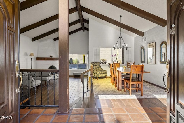 dining room with an inviting chandelier, beam ceiling, dark tile patterned flooring, and high vaulted ceiling