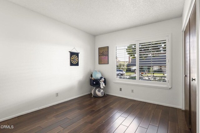 unfurnished room with dark wood-type flooring and a textured ceiling