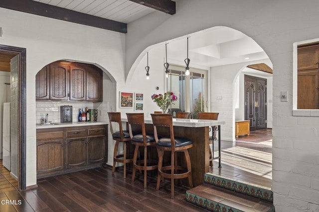 kitchen featuring wood ceiling, kitchen peninsula, beamed ceiling, a breakfast bar, and sink