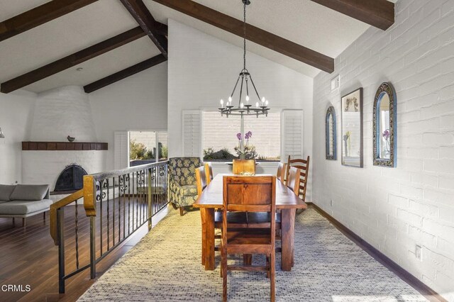 dining room with high vaulted ceiling, a large fireplace, beam ceiling, and a notable chandelier