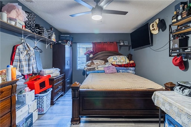 bedroom with ceiling fan, wood-type flooring, and a textured ceiling