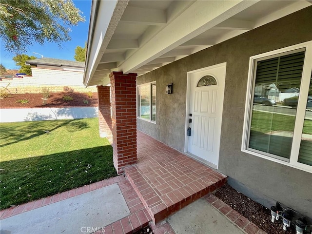 entrance to property with a patio area and a lawn