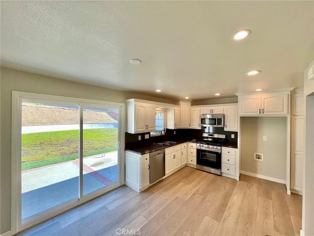 kitchen featuring appliances with stainless steel finishes, light hardwood / wood-style flooring, white cabinets, and sink