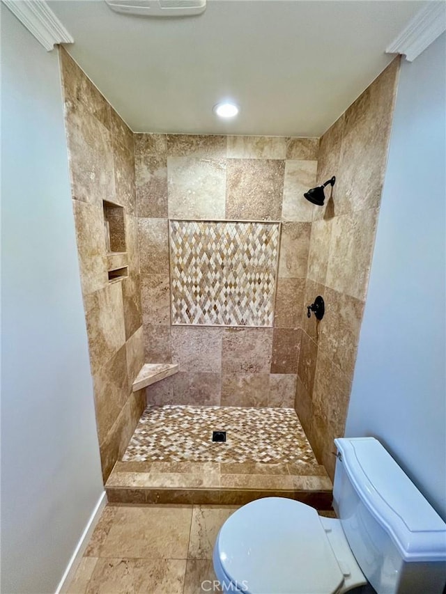 bathroom featuring toilet, crown molding, and tiled shower