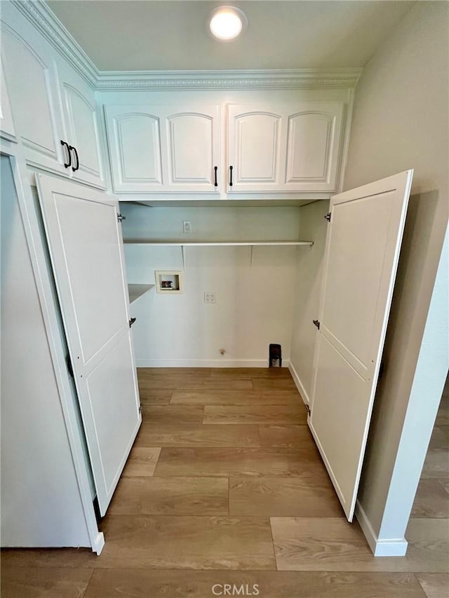 washroom featuring washer hookup, light hardwood / wood-style floors, and cabinets