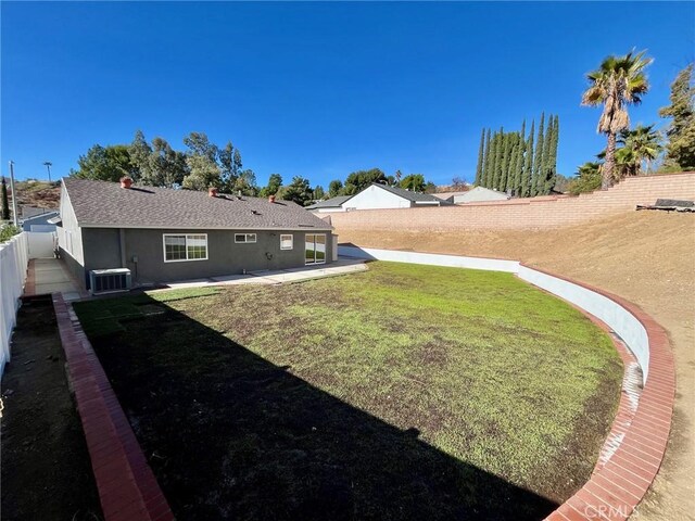 view of yard with central air condition unit and a patio