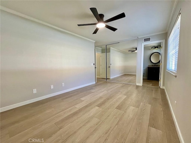 unfurnished bedroom featuring ceiling fan, light wood-type flooring, connected bathroom, ornamental molding, and a closet