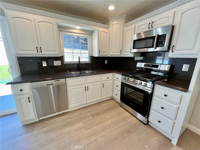 kitchen featuring light hardwood / wood-style floors, decorative backsplash, sink, white cabinetry, and appliances with stainless steel finishes