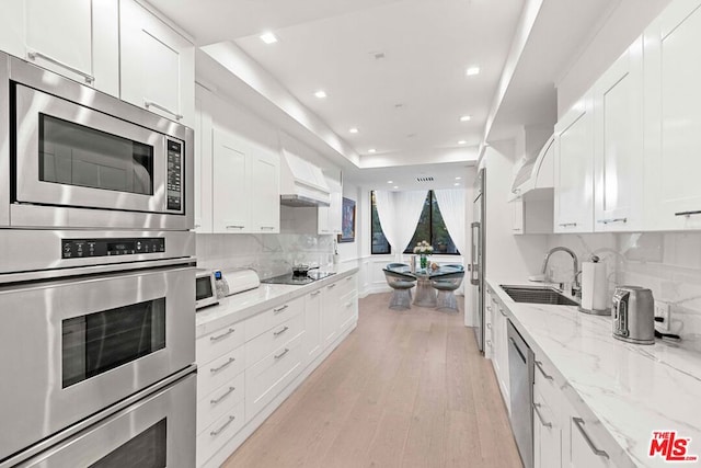 kitchen with white cabinetry, light stone counters, tasteful backsplash, and sink