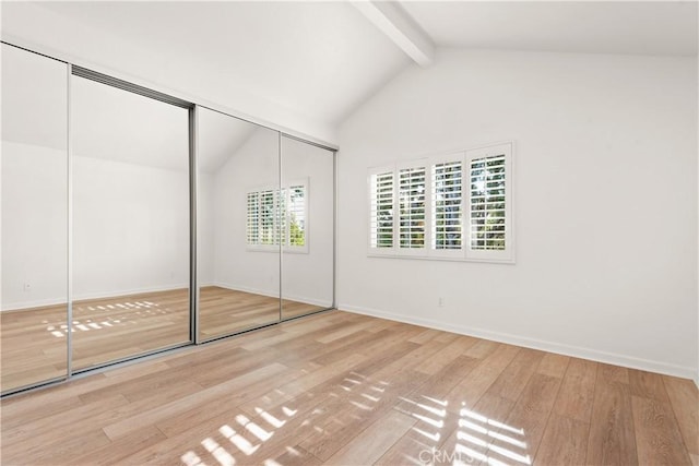 unfurnished bedroom with hardwood / wood-style floors, a closet, and vaulted ceiling with beams