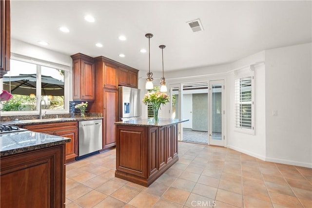 kitchen with a center island, appliances with stainless steel finishes, light tile patterned floors, sink, and pendant lighting