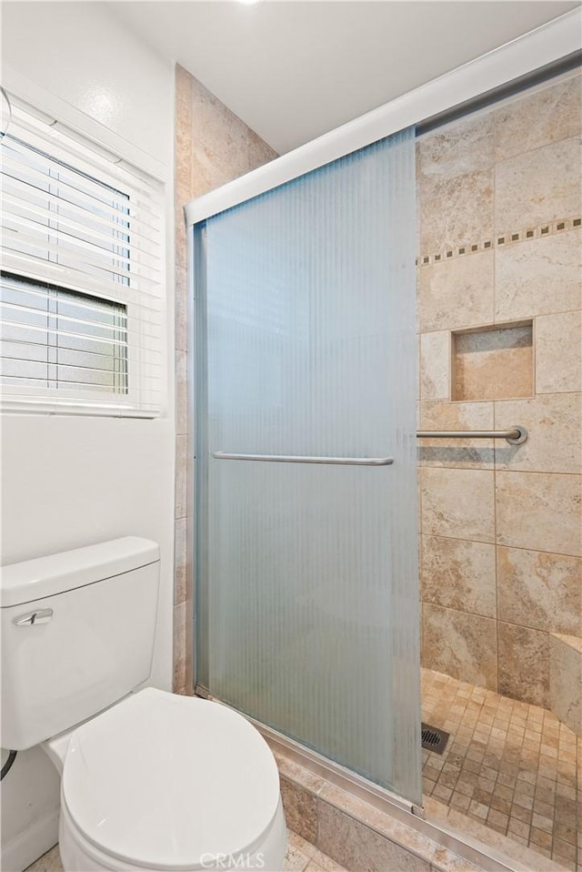 bathroom featuring toilet and a shower with door