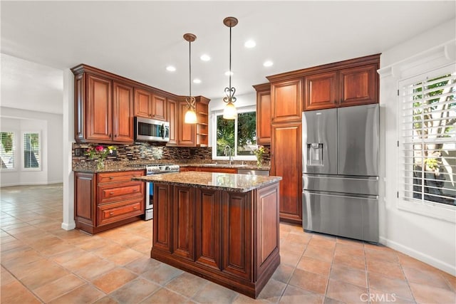 kitchen with decorative light fixtures, sink, dark stone counters, a kitchen island, and stainless steel appliances