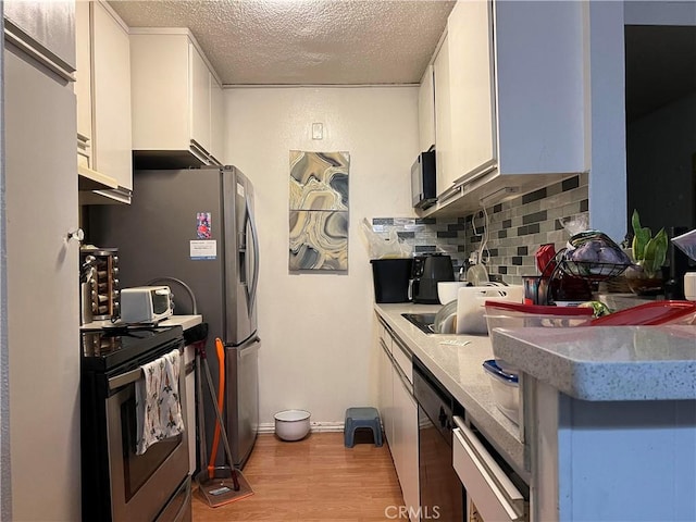 kitchen featuring stainless steel electric stove, black dishwasher, white cabinets, backsplash, and light hardwood / wood-style flooring