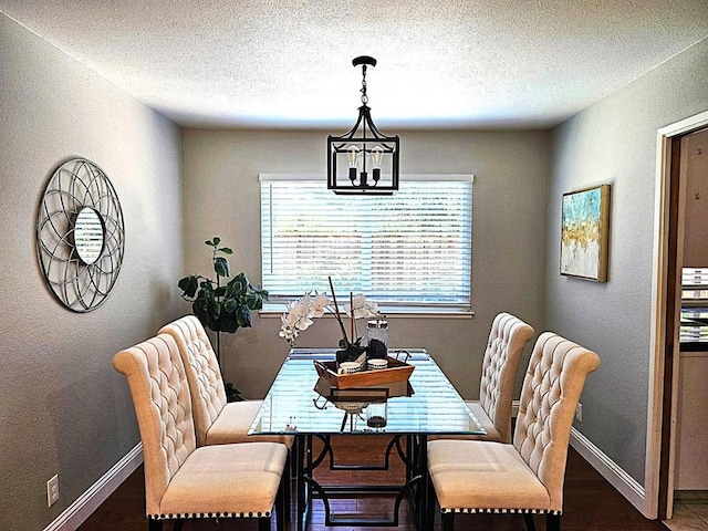 dining area featuring a textured ceiling, dark hardwood / wood-style floors, and a chandelier