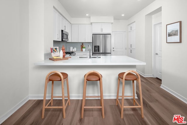 kitchen with a kitchen breakfast bar, kitchen peninsula, white cabinets, and stainless steel appliances