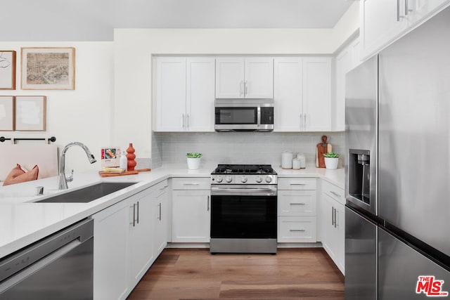 kitchen with backsplash, sink, white cabinetry, light hardwood / wood-style flooring, and appliances with stainless steel finishes