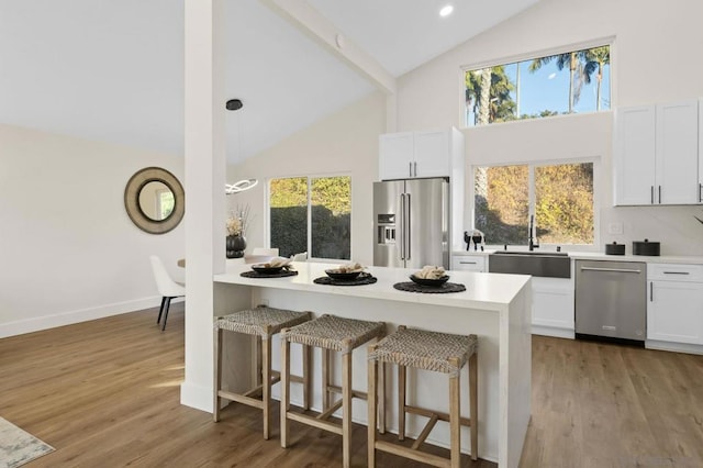 kitchen featuring white cabinetry, stainless steel appliances, sink, a kitchen breakfast bar, and light wood-type flooring