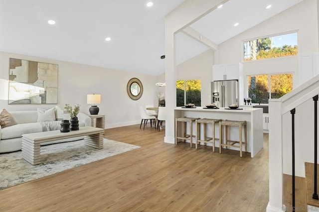 living room featuring high vaulted ceiling, a wealth of natural light, and light hardwood / wood-style flooring