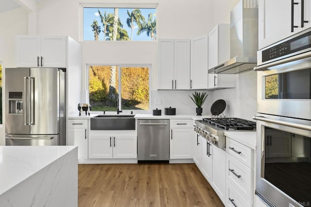 kitchen featuring white cabinets, wall chimney exhaust hood, sink, and stainless steel appliances