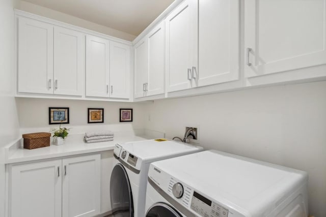 clothes washing area with cabinets and washing machine and clothes dryer