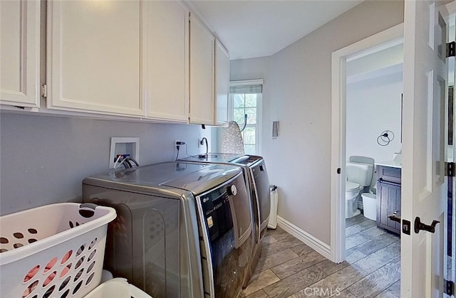 clothes washing area with washing machine and dryer and cabinets