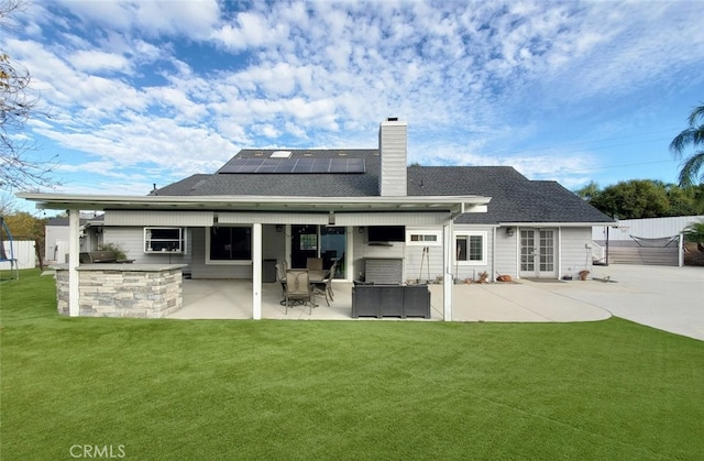 rear view of house with a patio area, a lawn, and solar panels