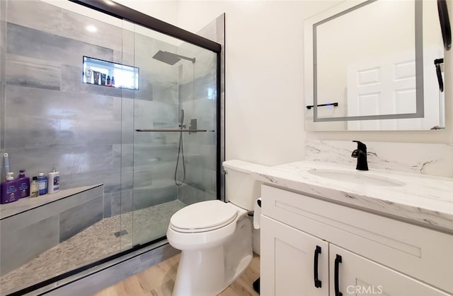 bathroom featuring wood-type flooring, toilet, walk in shower, and vanity