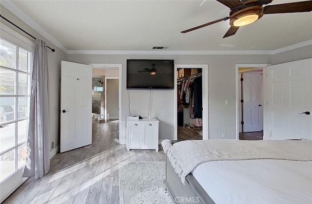 unfurnished bedroom with ceiling fan, light hardwood / wood-style floors, ornamental molding, a walk in closet, and a closet