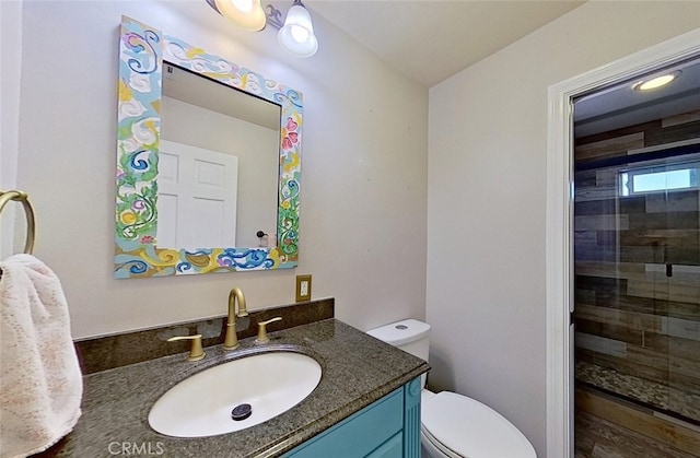 bathroom with a shower with shower door, toilet, and vanity