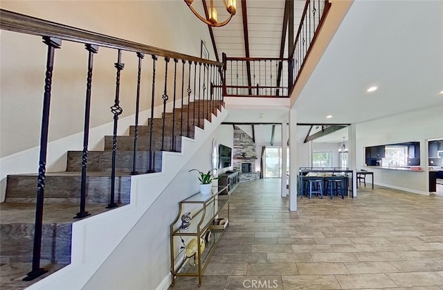 stairway featuring an inviting chandelier, a fireplace, and a high ceiling