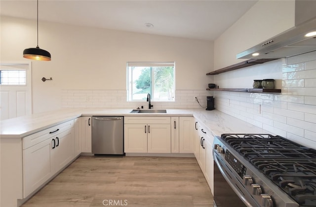 kitchen with white cabinets, appliances with stainless steel finishes, exhaust hood, sink, and kitchen peninsula