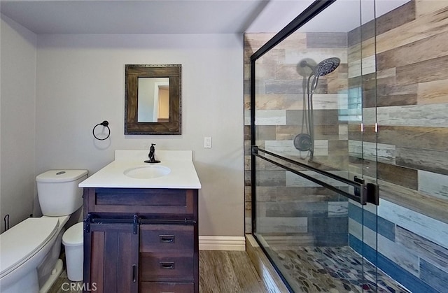 bathroom featuring toilet, hardwood / wood-style flooring, a shower with door, and vanity