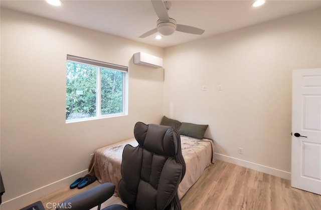 bedroom featuring ceiling fan, light hardwood / wood-style floors, and a wall mounted air conditioner