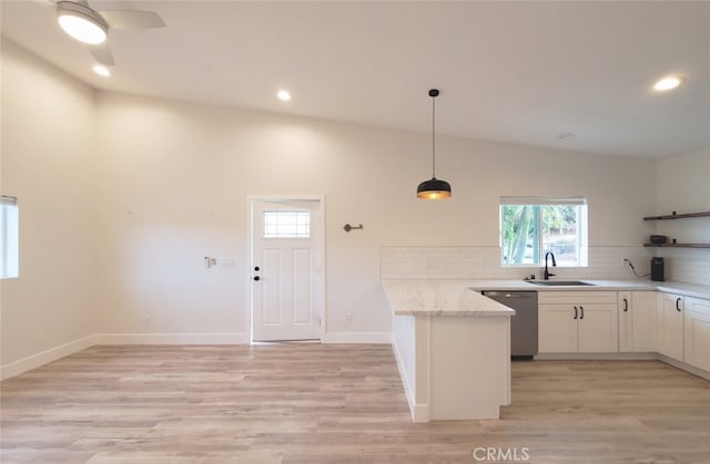 kitchen with decorative light fixtures, lofted ceiling, dishwasher, white cabinets, and light stone counters