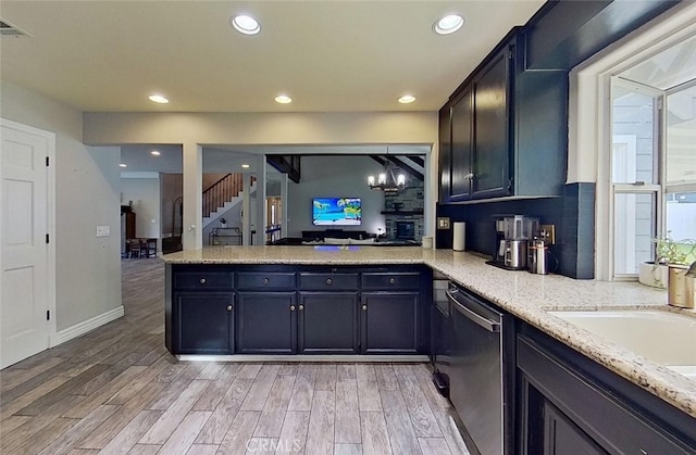 kitchen with dishwasher, kitchen peninsula, hanging light fixtures, light wood-type flooring, and plenty of natural light