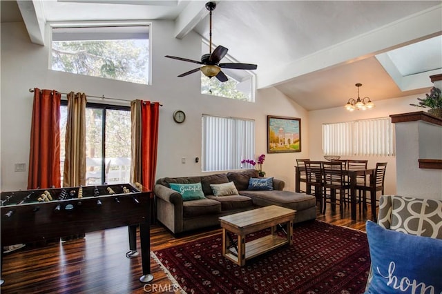 living room featuring ceiling fan with notable chandelier, a skylight, beamed ceiling, wood finished floors, and high vaulted ceiling
