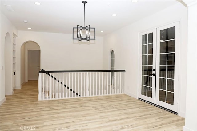 interior space with a notable chandelier, light hardwood / wood-style floors, and built in features